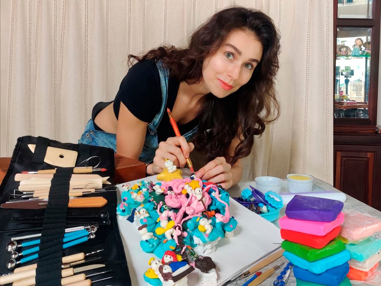 Rebeca Modena em seu ateliê, cercada por massinhas e sua obra